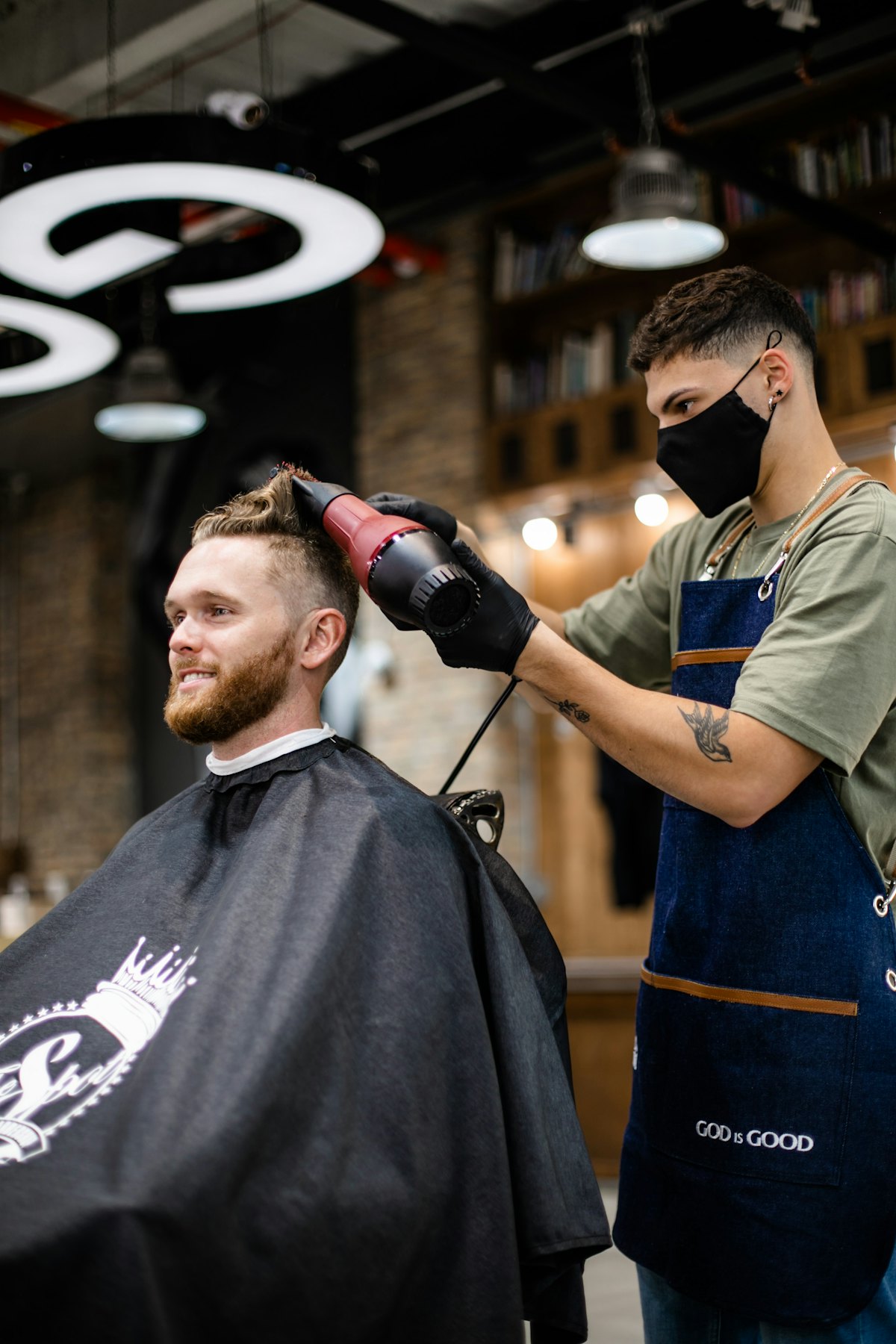 A barber blow-drying a client's hair in a salon